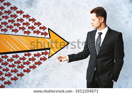 Businessman drawing group arrows on concrete wall. Leadership and way concept