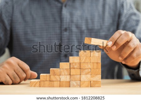 Close up male hand holding arranging or pick up the block wood game and stacking. Growth of Business financial investment and bankrupt concept.