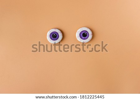 Festive Halloween gingerbread. Scary eyes with a pumpkin smile lie on a uniform orange background. Food for children for the holiday. Shooting from above. Greeting card, poster. Copy space, isolated