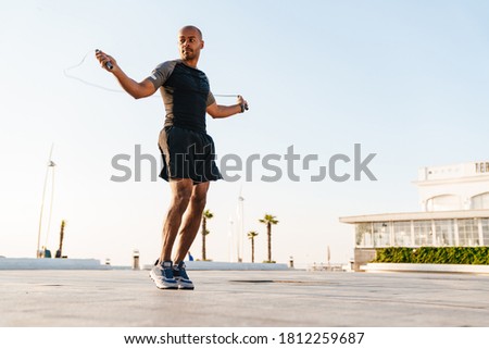 Image of athletic african american sportsman working out with jump rope outdoors Royalty-Free Stock Photo #1812259687