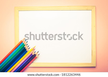 Colorful pencils near empty white frame. Education concept. Tonned image