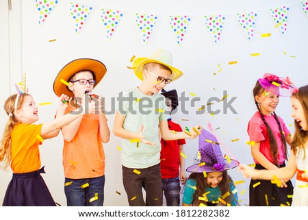 Adorable kids have fun together under colorful confetti