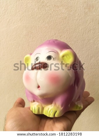 Cute of ceramic monkey close-up, piggy bank money background wall cement.