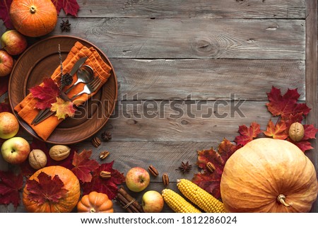 Autumn Thanksgiving Table Setting. Plate and cutlery on wooden table with pumpkins and autumn decor, Thanksgiving holiday menu concept.