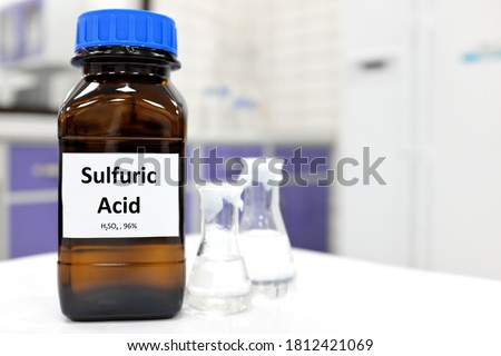 Selective focus of strong sulfuric acid chemical in brown amber glass bottle inside a laboratory with copy space. Royalty-Free Stock Photo #1812421069