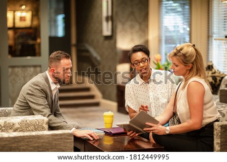 A shot of businessmen and businesswomen sitting in a lobby, they are talking business.