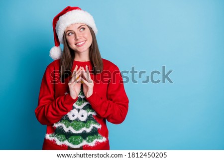 Photo of cute charming lady toothy white smiling look up empty space intrigued mad genius crazy minded wear santa x-mas headwear red ornamented pullover isolated blue color background