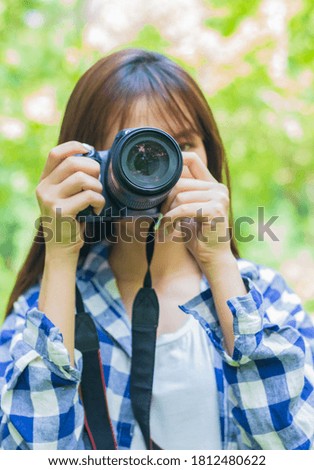 
Beautiful young travel photographer holding a camera on nature background