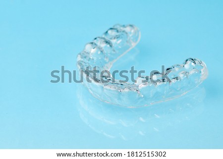 Close up invisible aligners on the blue background with copy space. Plastic braces dentistry retainers to straighten teeth. Royalty-Free Stock Photo #1812515302