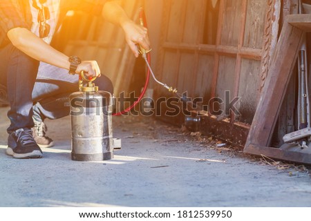 Employees at a termite control company are using a chemical sprayer to get rid of termites at customers' homes and search for termite nests to eradicate them. Chemical spray ideas to prevent insects. Royalty-Free Stock Photo #1812539950