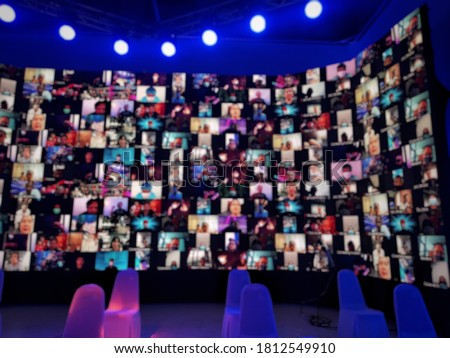 Blur large LED screen show many people's faces join big online event or virtual reality live conference. Big video call seminar, Work from home, Social distancing, New normal event production.   Royalty-Free Stock Photo #1812549910