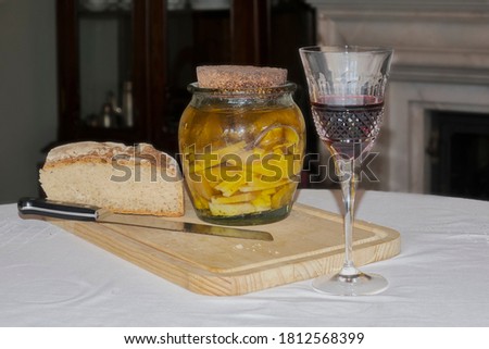 Still life composition, with a glass of wine, bread and old cheese in a glass container