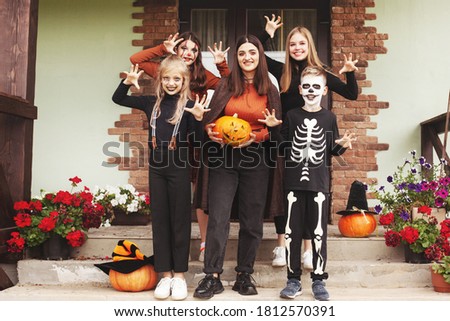 Happy kids celebrate halloween on the street near the house in costumes and make-up with pumpkin lantern jack,