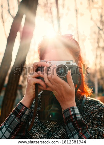 Close up of red-haired woman with retro camera in autumn park.