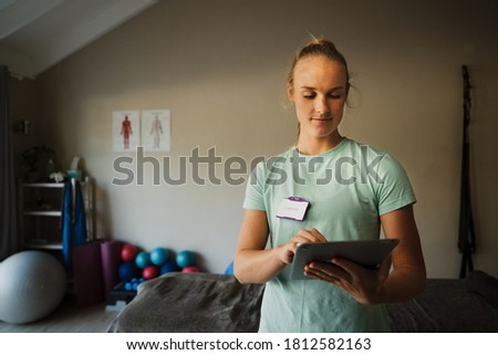 Beautiful Caucasian female therapist on digital tablet in medical, rehabilitation centre