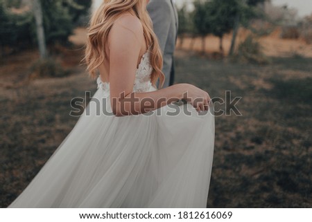 Bride walking with groom holding dress 