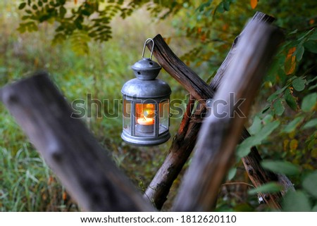 Ancient metal lantern with a burning candle on a wooden structure