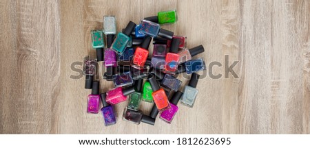 Background for design. A multi-colored bottles with nail polishes laid out on the wooden table