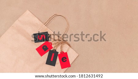 
Craft bag with red and black tags with 'SALE' lettering on brown texture. Online sales of China 11.11. View from above. With place for text.