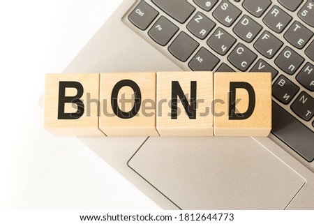 Word bond. Wooden cubes with letters isolated on a laptop keyboard. Business Concept image.