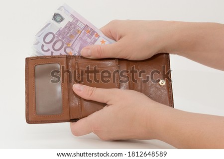 Close-up on white background female hands take out banknotes from brown wallet. Horizontal photo. Concept - payment, waste, purchases