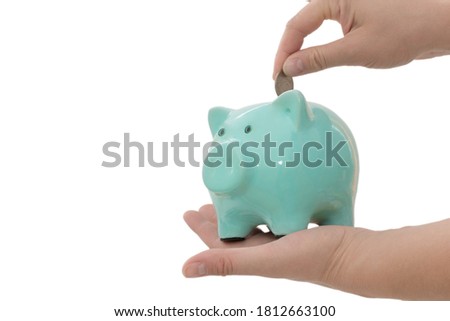 Close-up on a white background female hands, On the hand a piggy bank, and the second folds a coin. The concept is respect for money, saving, saving. Horizontal photo Royalty-Free Stock Photo #1812663100