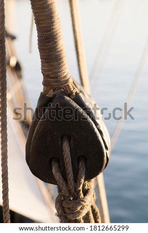 Selective focus of a Wood pulley with a rope with a blurry background with the surface of the sea 