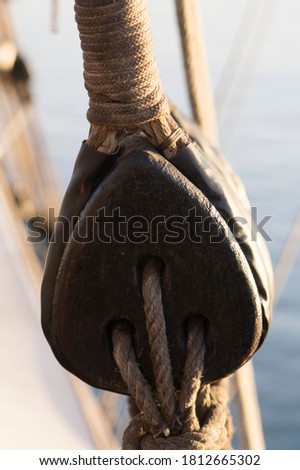 Selective focus of a Wood pulley with a rope with a blurry background with the surface of the sea 