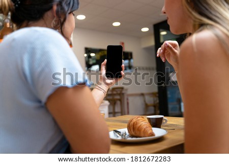 Detailed shot of two young women making a video call, speaking in sign language. Deaf friends or couple communicating, having fun, having a nice conversation, sitting together