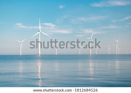 offshore windmill park with stormy clouds and a blue sky, windmill park in the ocean. Netherlands Europe Royalty-Free Stock Photo #1812684526