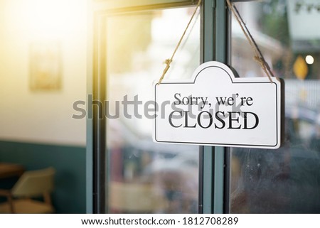 text on white sign "Sorry, we're closed" hanging in front door cafe Royalty-Free Stock Photo #1812708289