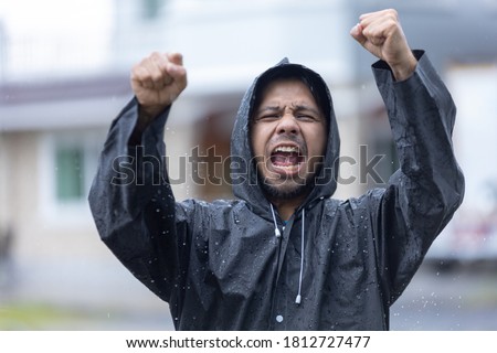 happy asian man with arms open in the rain