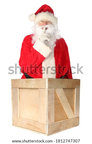 Santa Claus stands in a Shipping Container with is finger to his mouth saying he has a Secret. Isolated on white. Room for text. Christmas Holiday Concept.