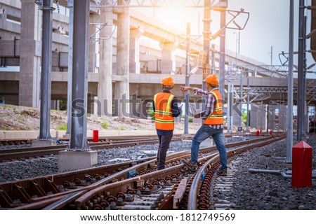 Engineer under discussion inspection and checking construction process railway switch and checking work on railroad station .Engineer wearing safety uniform and safety helmet in work. Royalty-Free Stock Photo #1812749569