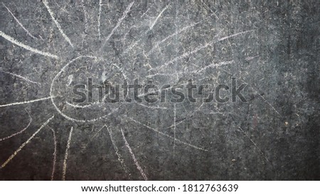 A chalk drawing of a smiling sun on a drawing board
