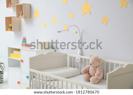 Crib with toy bear in stylish baby room interior Royalty-Free Stock Photo #1812780670