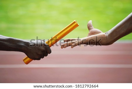 Two men passing golden baton in stadium. Conceptual image shot Royalty-Free Stock Photo #1812792664