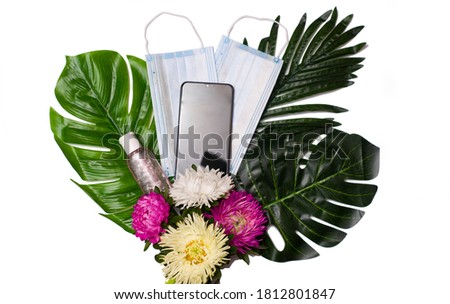 Creative flat lay view from above. Bouquet of medical masks, antiseptic, phone. Minimal tropical palm leaf plants summer concept template for your text or design