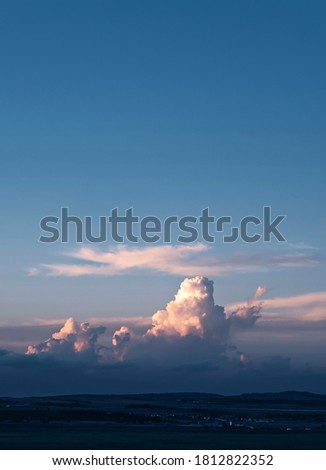 The setting sun illuminates the cumulus clouds over the valley. Beginning of autumn. Vertical photo with copy space