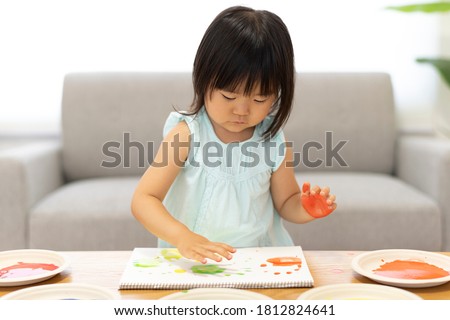A girl puts paint on her hand and draws a picture