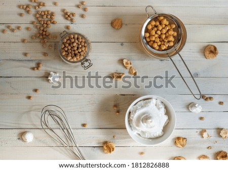 dry chickpea seeds, and whipped to a froth aquafaba on a light wooden table. Top view with space,horizontal
