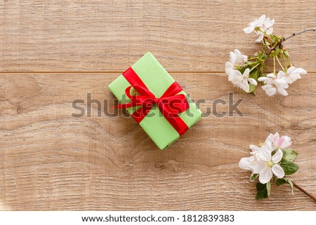 Gift box with branches of flowering cherry and apple trees on the wooden background. Top view. Concept of giving a gift on holidays.