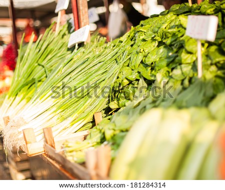 Fresh leeks, spinach and squashes on an open market stall.