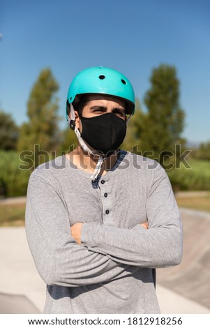 male roller skater with t-shirt, protective helmet and coronavirus prevention mask (new post covid normality) in a skate park