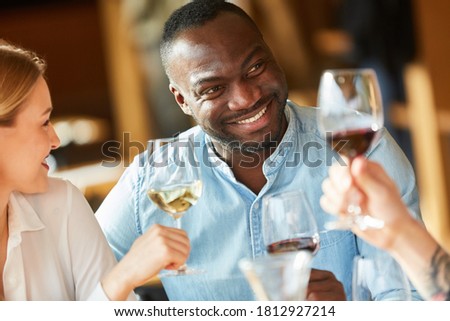 African man having wine together with friends in a bar