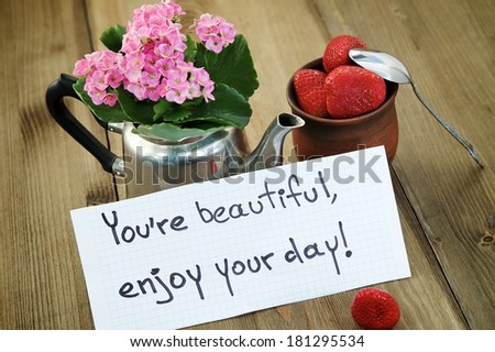 "You're beautiful, enjoy your day" inscription on the background of the cup with strawberries