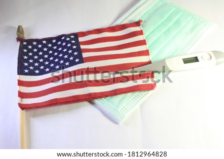 American flag and COVID-19 face mask and thermometer