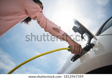 Female silhouette charging a electric car, photo from below Royalty-Free Stock Photo #1812967399