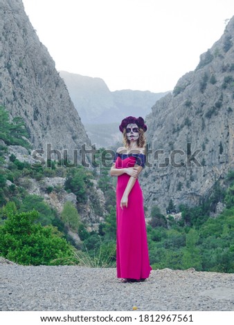 Santa Muerte makeup woman in pink dress on Halloween eve outdoors mountain background