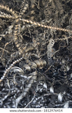 Steel scrap materials recycling. Aluminum chip waste after machining metal parts on a cnc lathe. Closeup twisted spiral steel shavings. Small roughness sharpness, possible granularity, blurred focus 